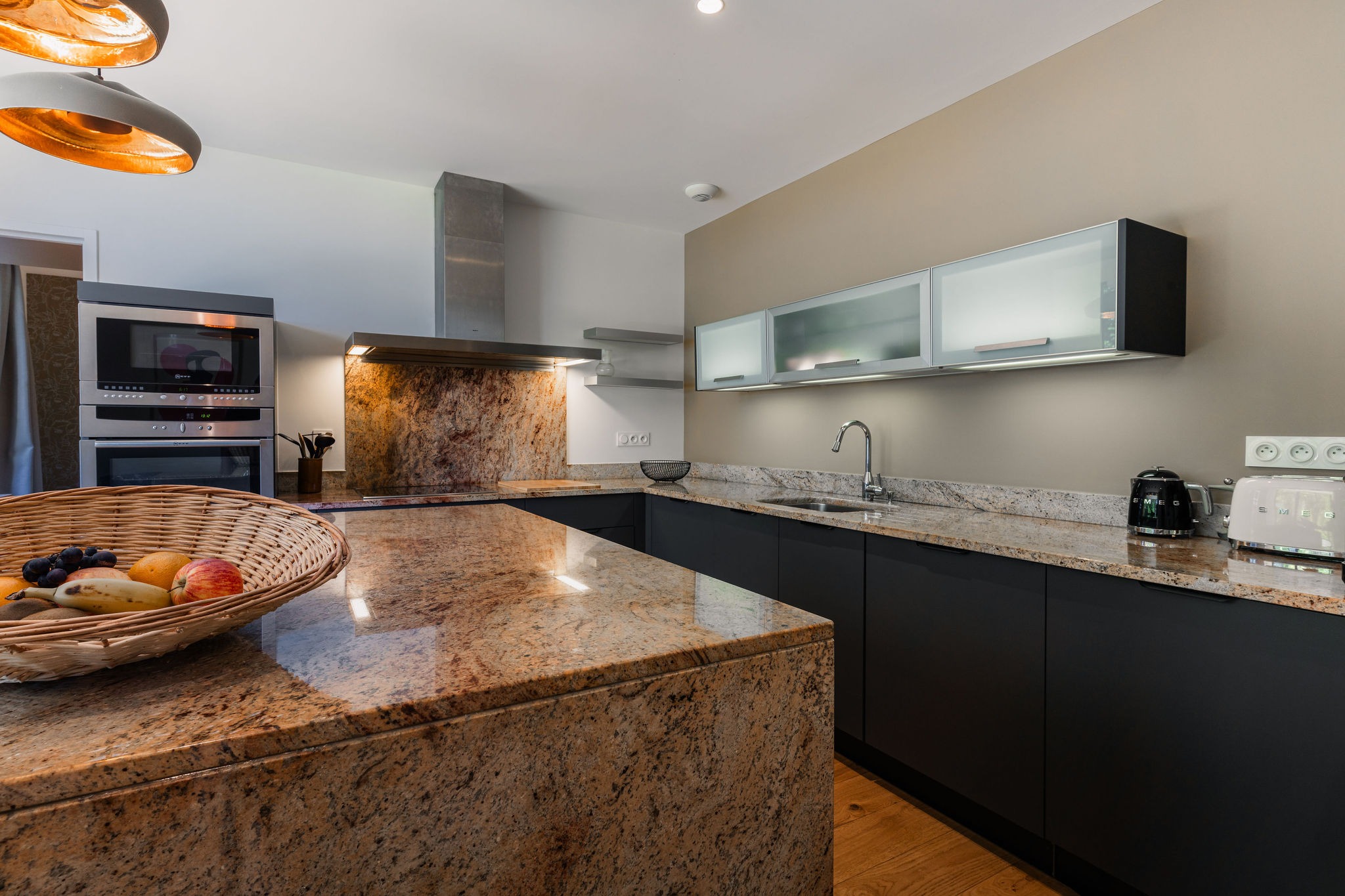 Cuisine contemporaine avec plans de travail en pierre naturelle et électroménager haut de gamme dans l’appartement Le Corentin, vue mer sur les Glénan, Domaine de Stang Bihan.