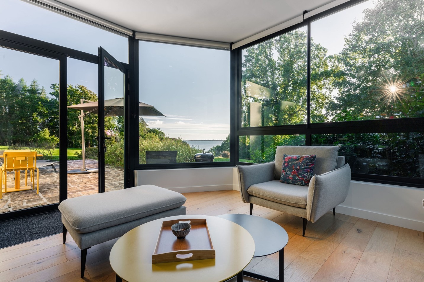 Salon moderne de l'appartement Le Corentin avec larges baies vitrées donnant sur une terrasse, vue mer panoramique à 180° sur les Glénan, dans le domaine de Stang Bihan à Concarneau.