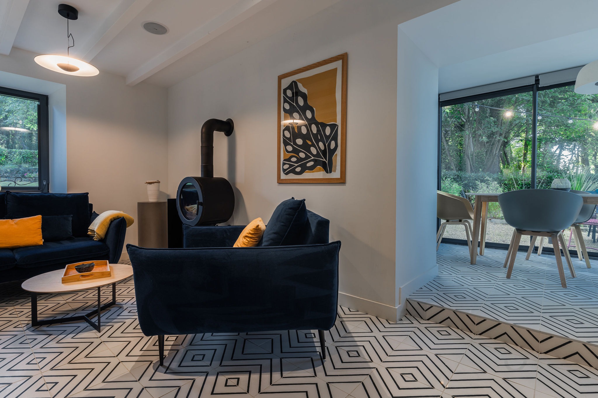 Salon du logement le Sant C’hireg au Domaine de Stang Bihan, avec poêle à bois, canapé cosy et espace repas en véranda