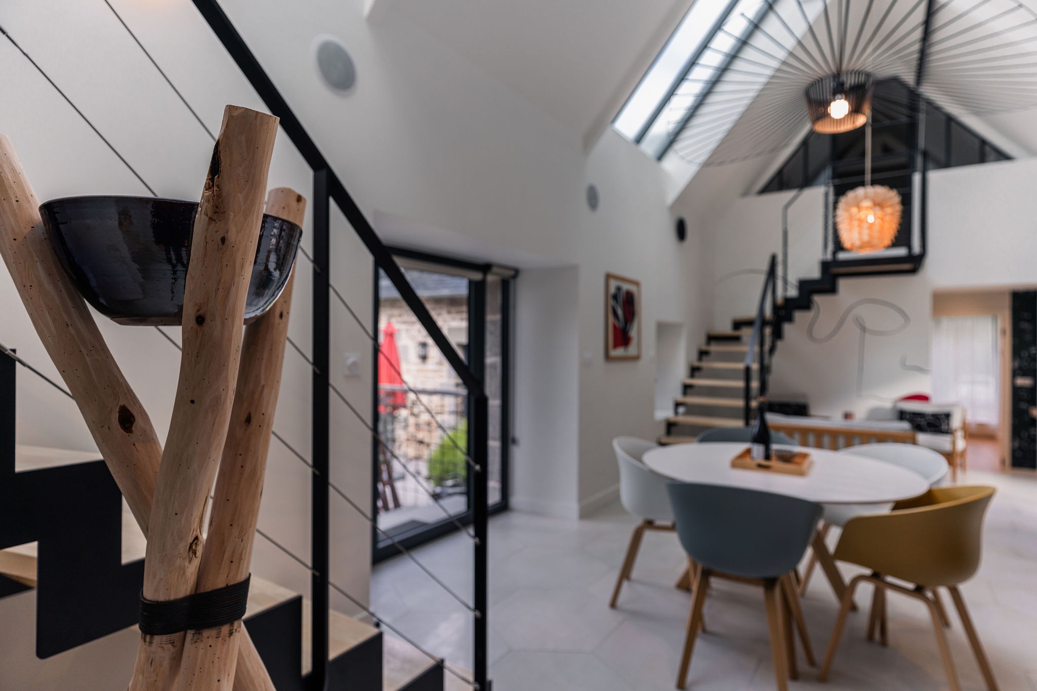 Vue intérieure du gîte L’Étoile du Roy avec coin repas, double escalier design, puits de lumière et accès terrasse