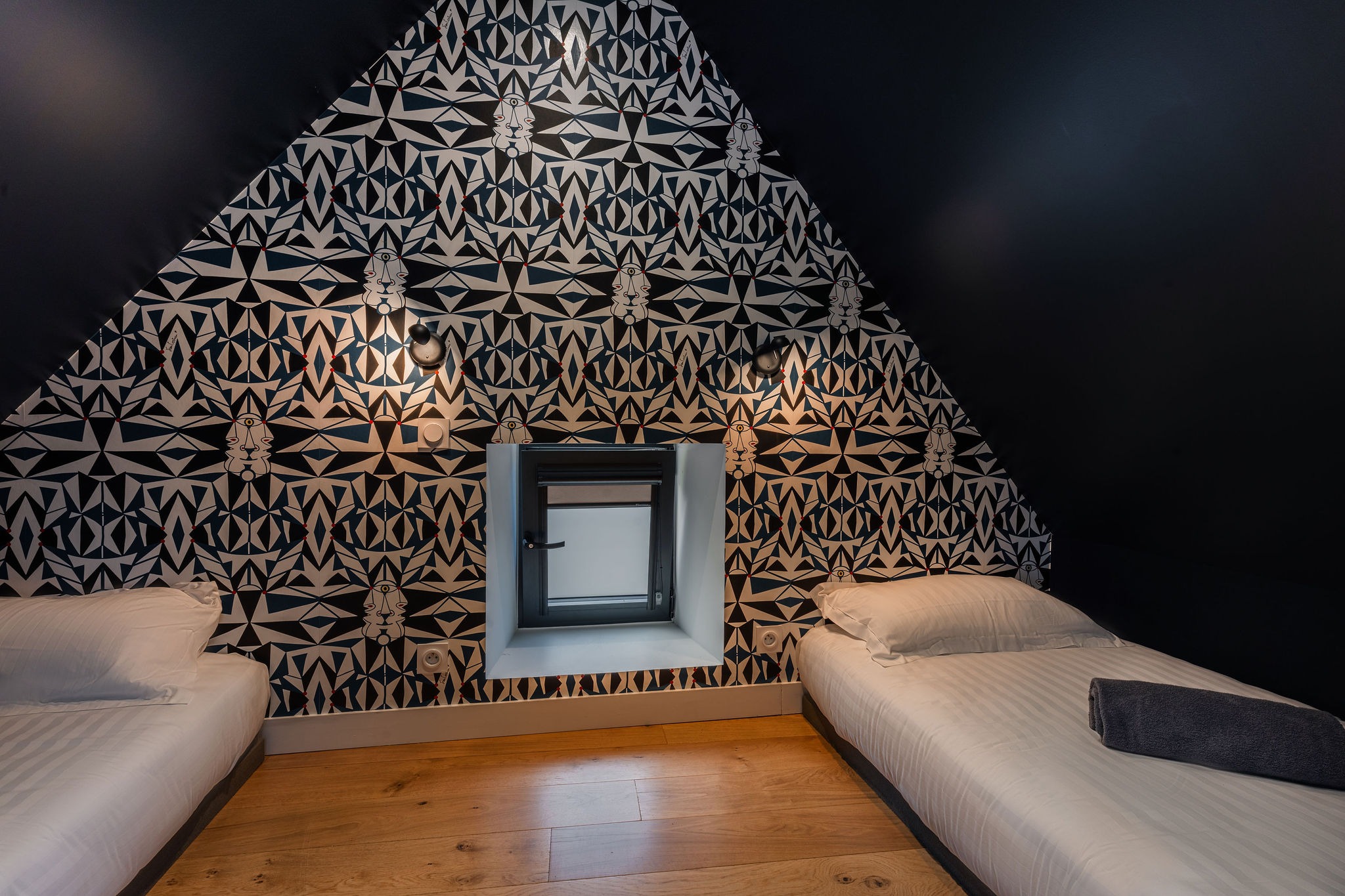 Chambre enfants originale sous combles avec deux lits simples et papier peint graphique au gîte L’Étoile du Roy
