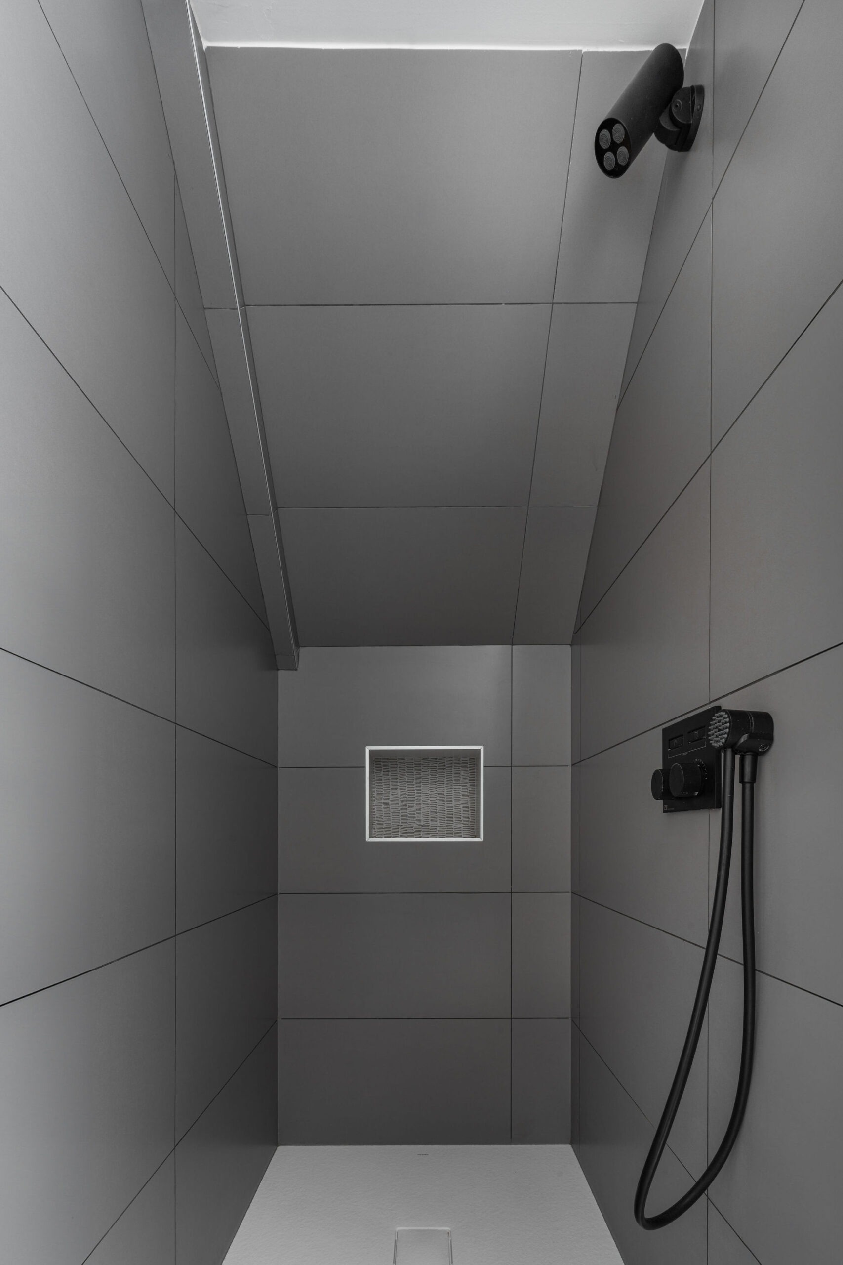 Douche à l'italienne avec carrelage gris et accessoires noirs dans le logement Belem, résidence de luxe au Manoir de Stang Bihan à Concarneau.