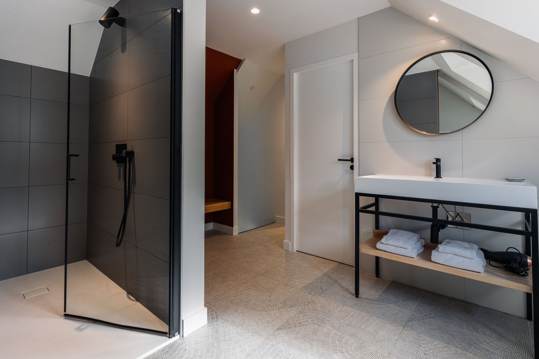 Salle de bain du Belem avec douche à l'italienne vitrée, lavabo moderne avec étagère en bois, et carrelage au sol, dans une dépendance du Manoir de Stang Bihan à Concarneau.