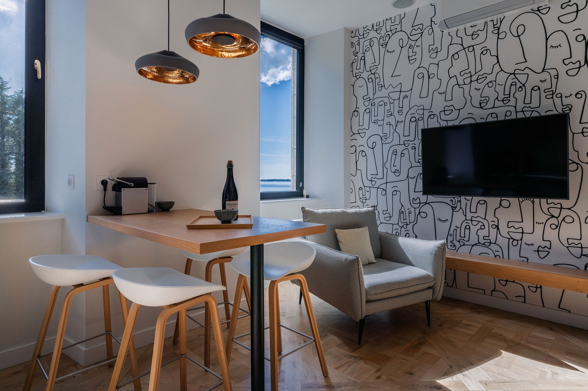 Salon moderne de l’appartement La Fée de l’Aulne au Domaine de Stang Bihan, avec coin repas, fauteuil design, vue mer et décoration murale contemporaine