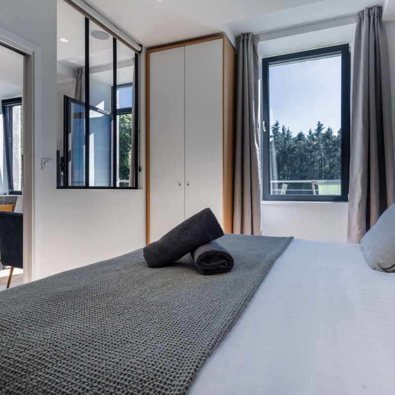 Chambre double lumineuse avec vue sur jardin et mer, verrière intérieure sur le salon – Appartement Le Biche, Domaine de Stang Bihan à Concarneau