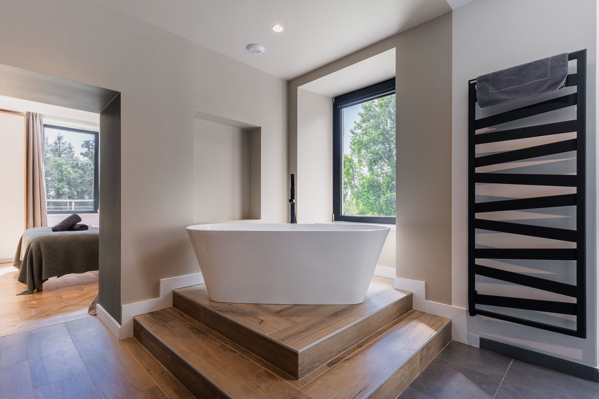 Baignoire îlot sur estrade en bois avec vue sur la nature – Salle de bain de l’appartement Le Biche, Domaine de Stang Bihan